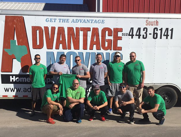 The Advantage Moving crew, in green and gray company shirts, in front of their branded moving trailer